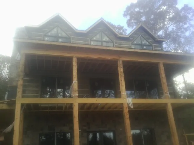 Dormers and porch framing on a large log home under construction — Roof Coating work by our crew in Galesville