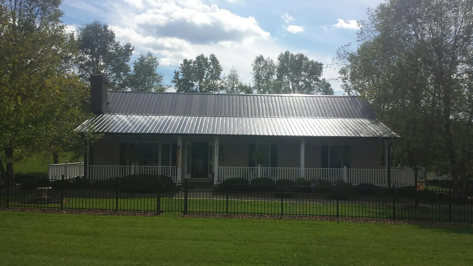 Gray metal roof on a brick ranch with a full width front porch — Gutter Guard Installation work by our crew in Galesville