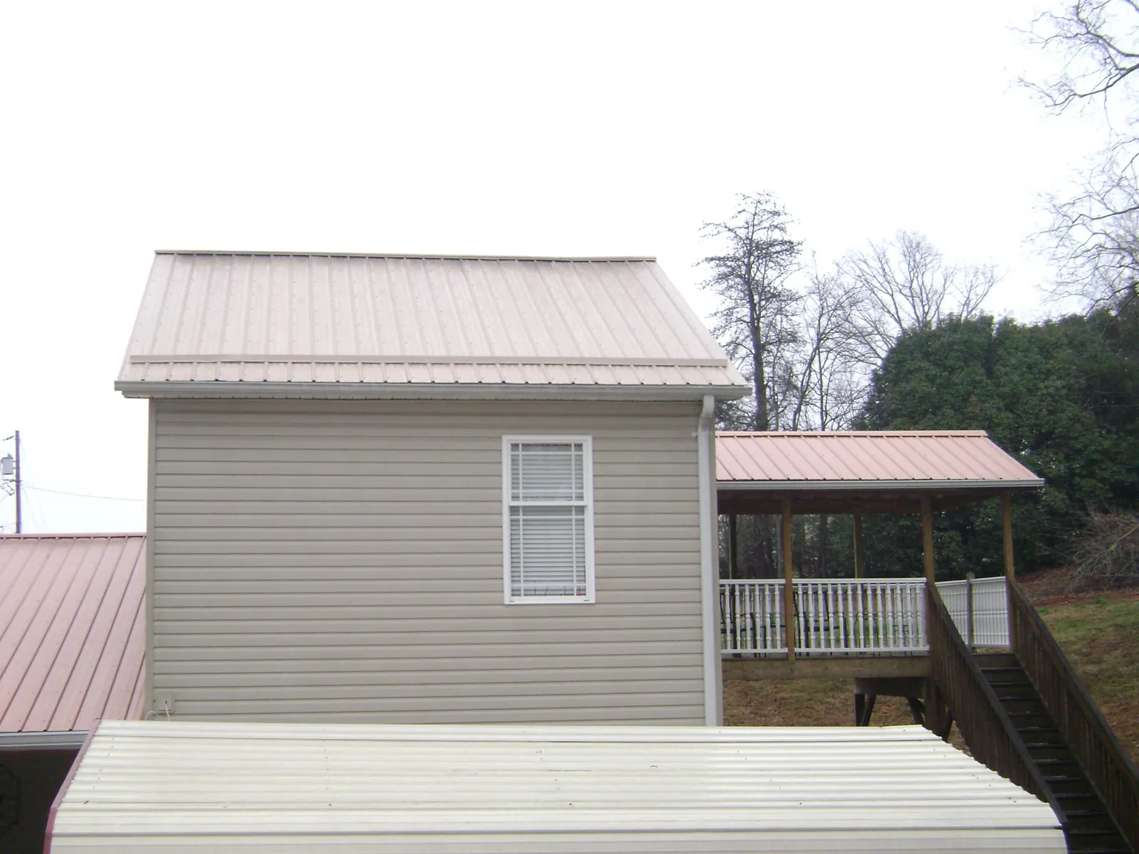 Tan metal roofs on a two story addition and attached porch, from a Roof Replacement job in Galesville
