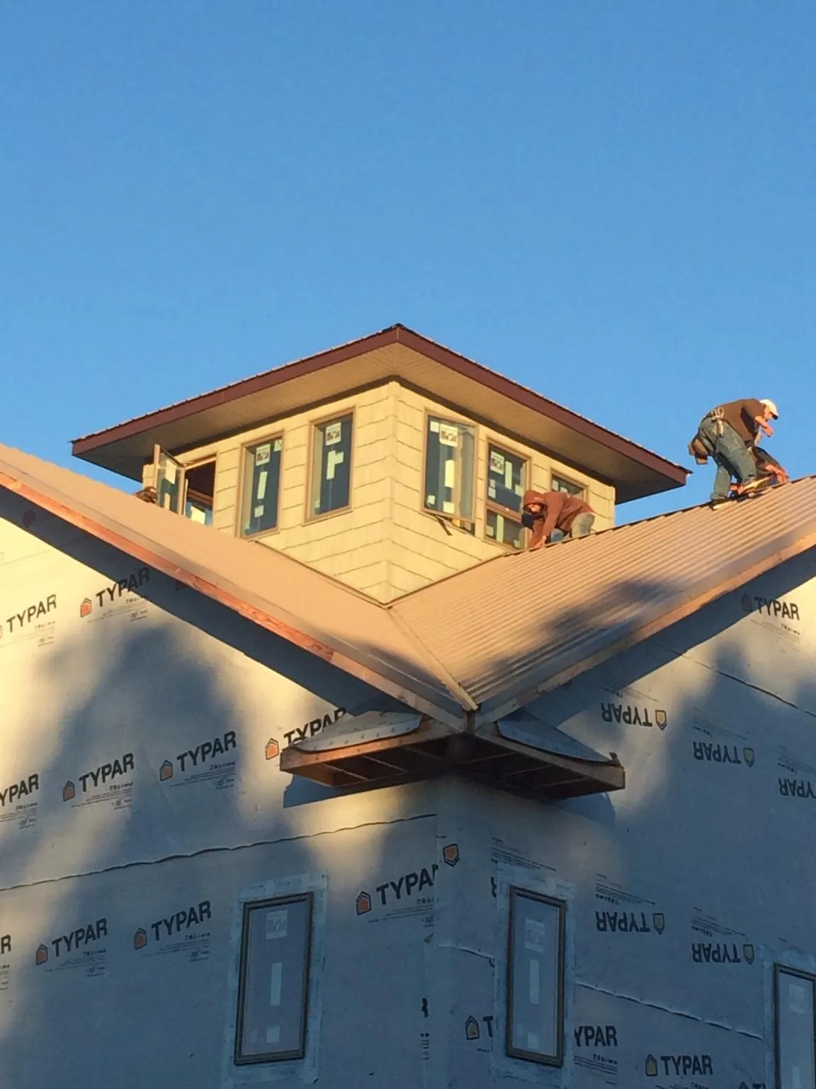 Roofers working around a rooftop cupola on a new metal roof at sunset — Roof Waterproofing in Galesville by Roofing Brothers